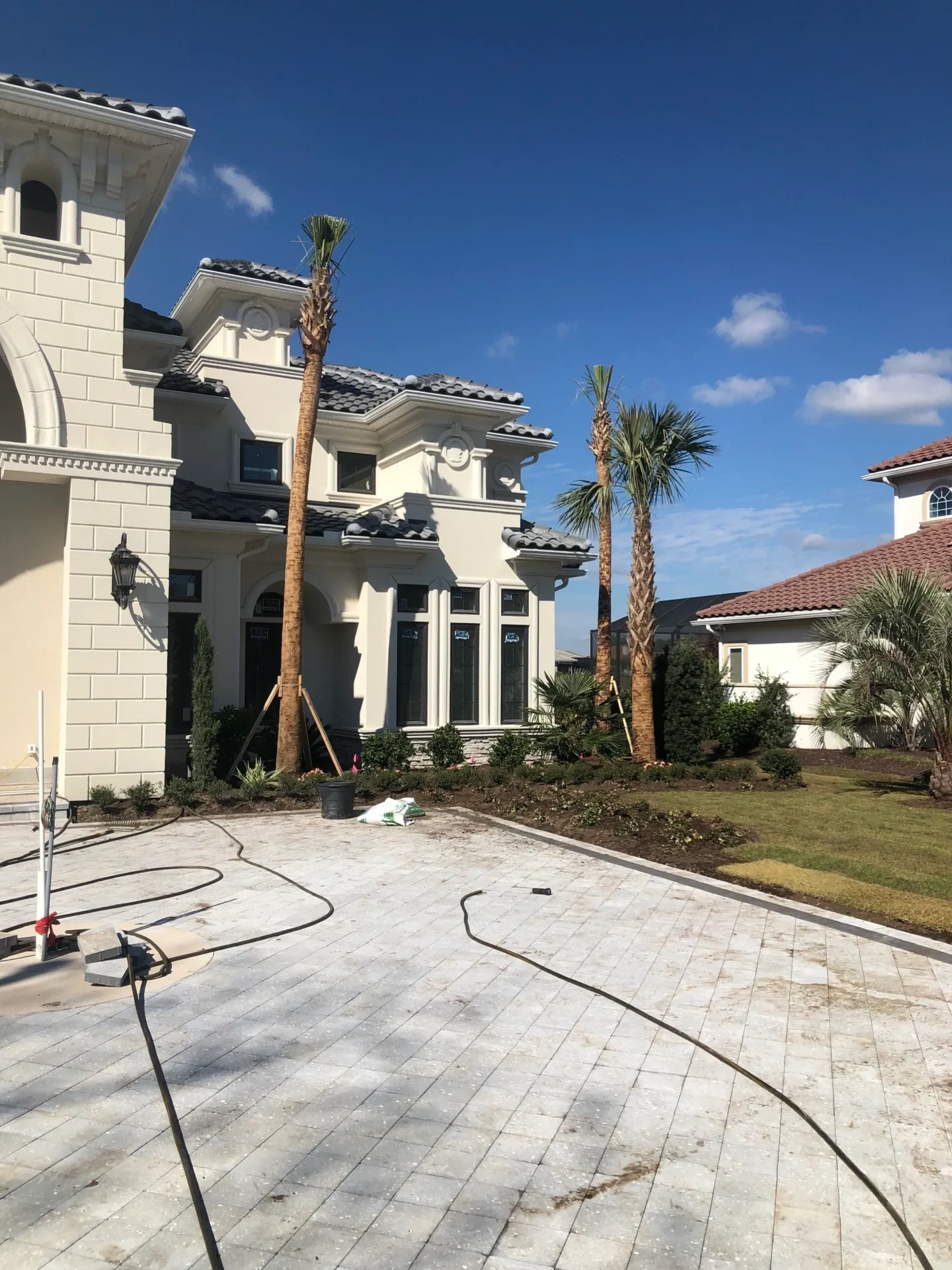 A large white house with palm trees and a power washer.