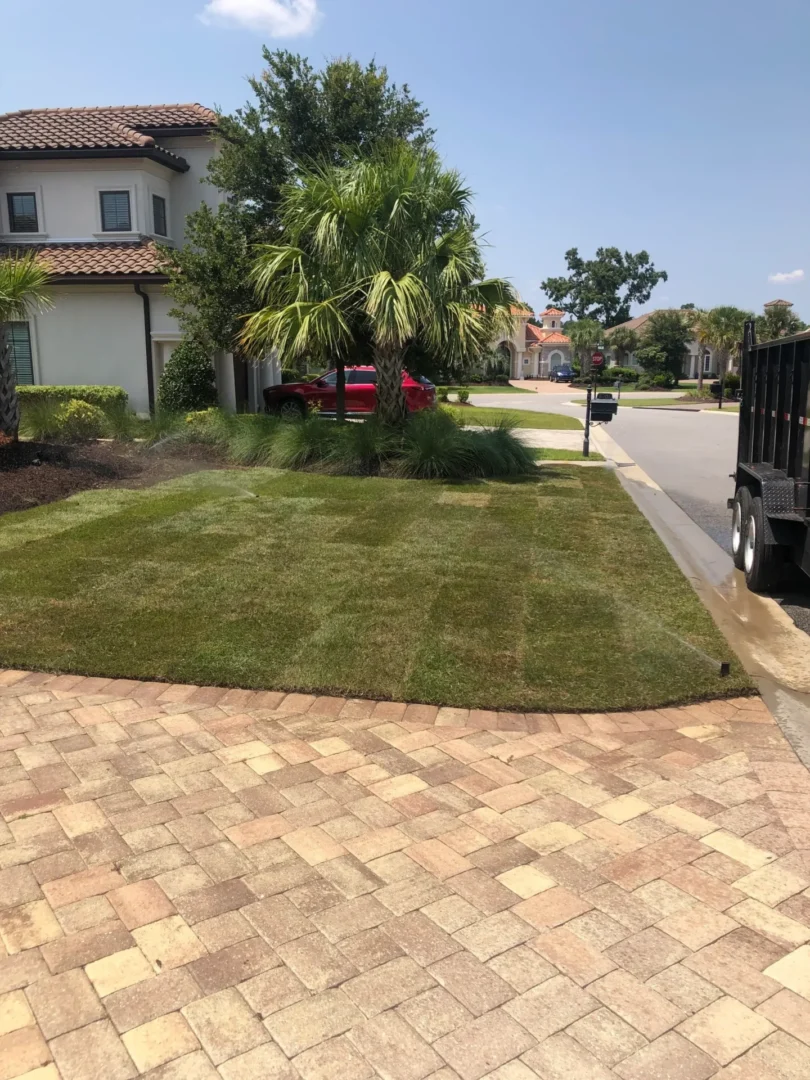 A driveway with brick pavers and grass in the middle of it.