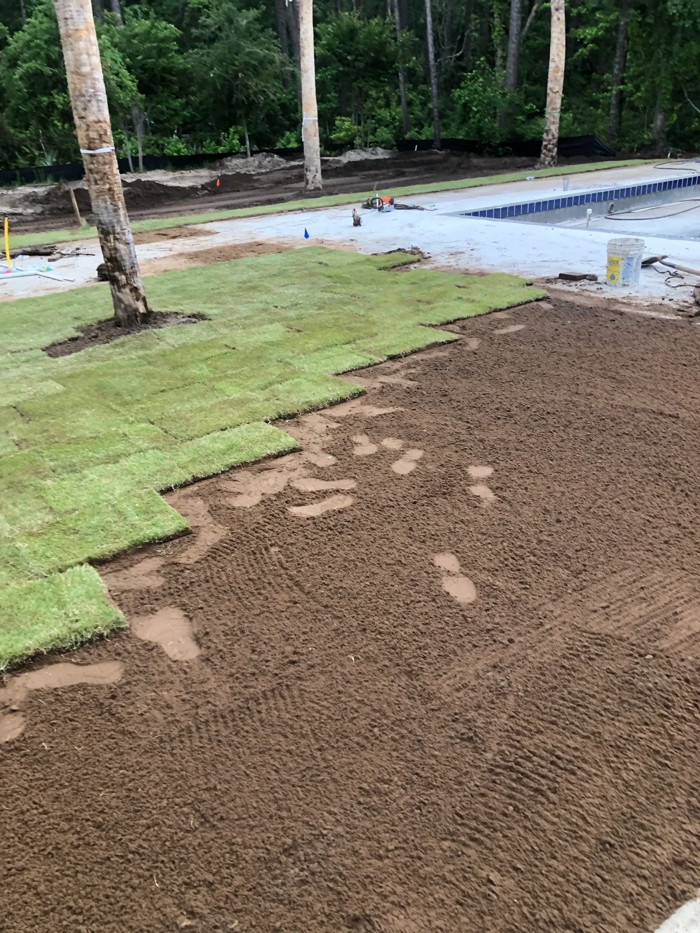 A green patch of grass is being laid on the ground.