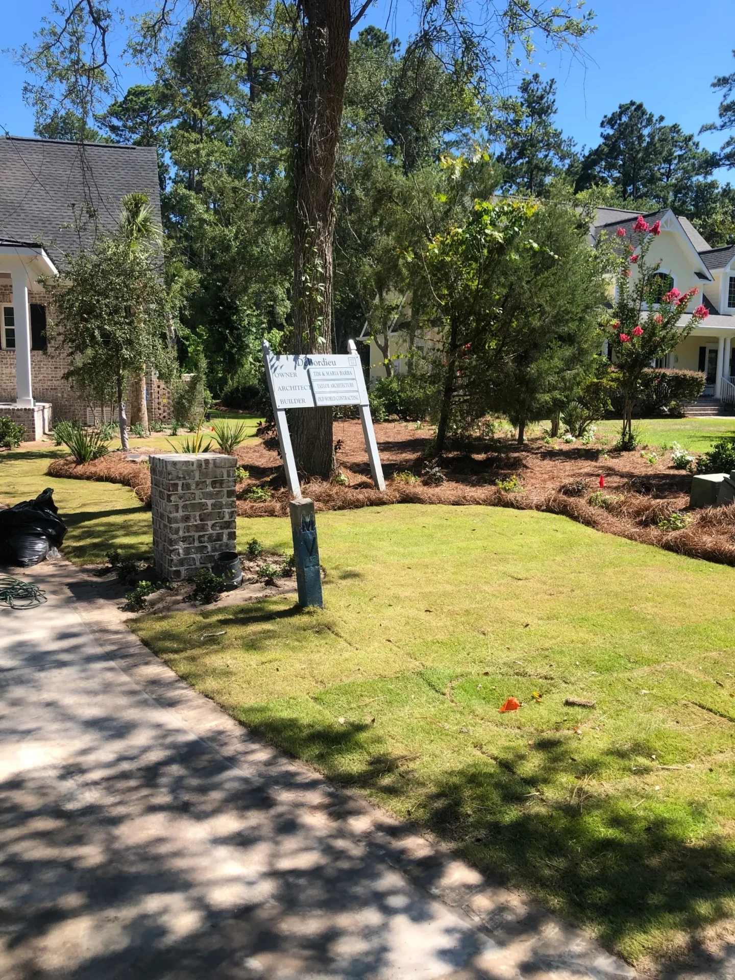 A sign in the middle of a yard with trees.